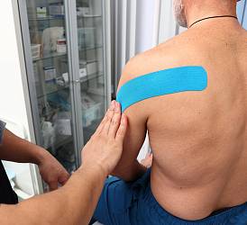 Специалист по массажу, гирудотерапевт Пак Д.В. накладывает кинезиотейпы