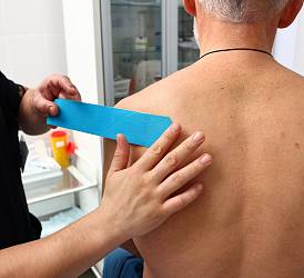 Специалист по массажу, гирудотерапевт Пак Д.В. накладывает кинезиотейпы